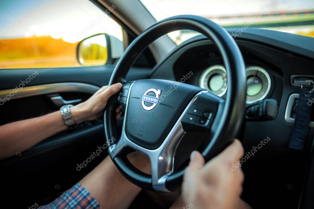 BERLIN / GERMANY - APRIL 29, 2018: Driver in shorts holds a Volvo steering wheel during car ride on freeway.