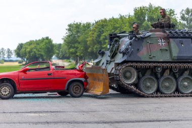 Feldkirchen / Almanya - 9 Haziran 2018: Alman tankı dozer Dachs Feldkirchen Bundeswehr gününde bir kırmızı araba çöker.