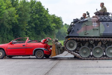 Feldkirchen / Almanya - 9 Haziran 2018: Alman tankı dozer Dachs Feldkirchen Bundeswehr gününde bir kırmızı araba çöker.