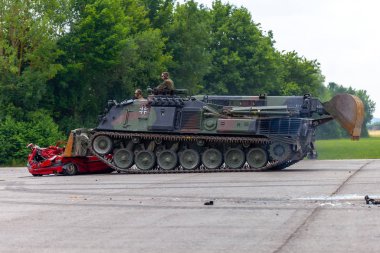 Feldkirchen / Almanya - 9 Haziran 2018: Alman tankı dozer Dachs Feldkirchen Bundeswehr gününde bir kırmızı araba çöker.