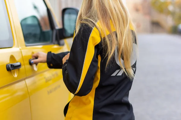 Berlin / Almanya - Kasım 9,2018: Deutsche Post ve Dhl kadın postacı sarı postcar üzerinde.