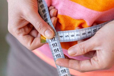 woman measures her abdomen with a measuring tape clipart