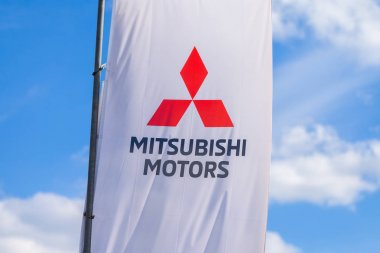 NUREMBERG / GERMANY - APRIL 7, 2019: Mitsubishi logo on a Mitsubishi flag at a car dealer. Mitsubishi Motors Corporation is a Japanese multinational automotive manufacturer headquartered in Japan. clipart