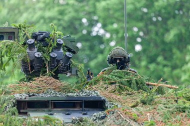 Alman askeri tam kamuflajlı bir askeri araç üzerinde oturuyor