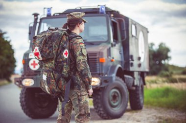 HANNOVER / GERMANY - 22 HAZİRAN 2020: Alman ordusunun acil durum çantalı sağlık görevlisi askeri ambulansın yanında duruyor