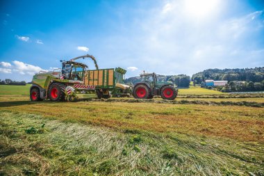 BAVARIA / GERMANY - AĞUSTOS 07.2020: Claas hasatçısı ve Krone ZX400GL karavanı olan bir Fendt 926 bir tarla üzerinde çalışıyor.