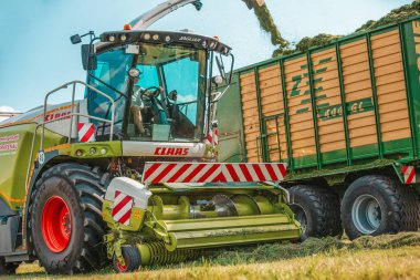 BAVARIA / GERMANY - AĞUSTOS 07,2020: Claas Jaguar 930 hasat aracı ve Krone ZX400GL karavanı olan bir Fendt 926 bir tarla üzerinde çalışıyor.