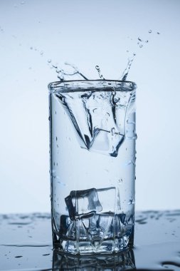 Splash su buz dilim beyaz arka plan yakın çekim üzerinde Kupası Cam