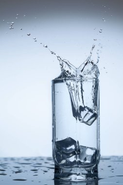 Splash su buz dilim beyaz arka plan yakın çekim üzerinde Kupası Cam