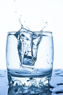 bir parça buz beyaz bir arka planda su sprey damlacıkları ile bir sıçrama ile bir bardak su sıçrama