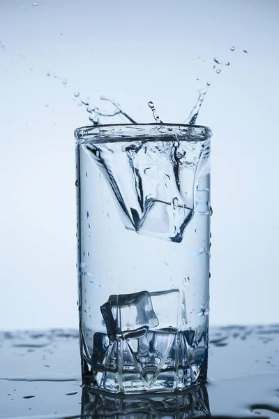 splash of water in glass Cup with ice slice on white background close-up