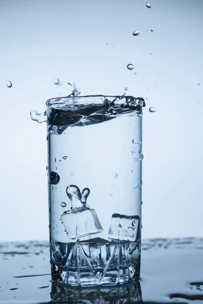 splash of water in glass Cup with ice slice on white background close-up