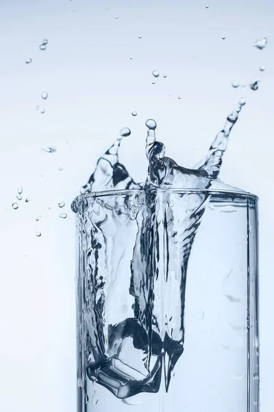 splash of water in glass Cup with ice slice on white background close-up