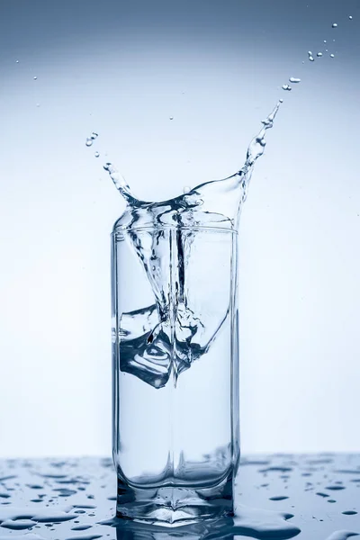 splash of water in glass Cup with ice slice on white background close-up