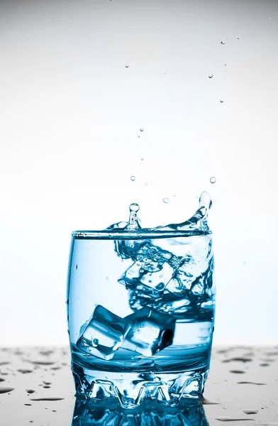 Water Splash Een Glas Met Een Stuk Ijs Een Witte — Stockfoto