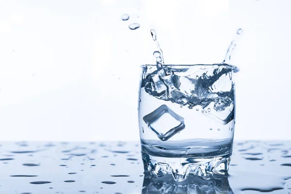 Water Splash Een Glas Met Een Stuk Ijs Een Witte — Stockfoto