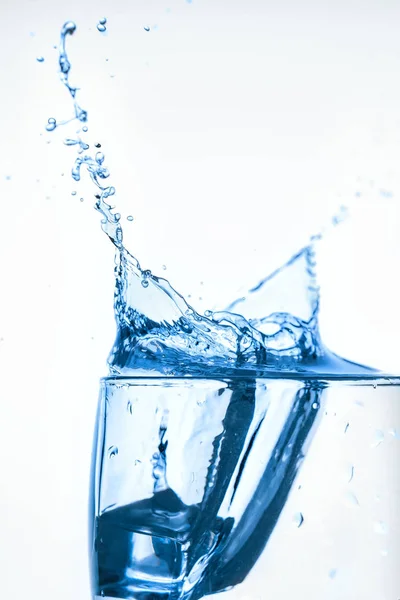 splash of water in glass Cup with ice slice on white background close-up