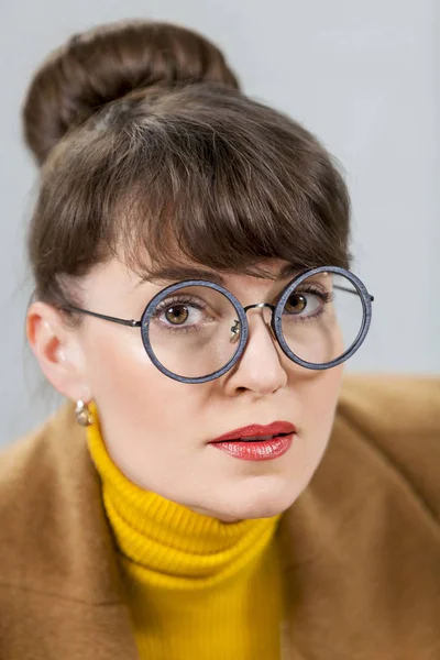 灰色の背景に丸いメガネのクローズ アップの女の子 — ストック写真