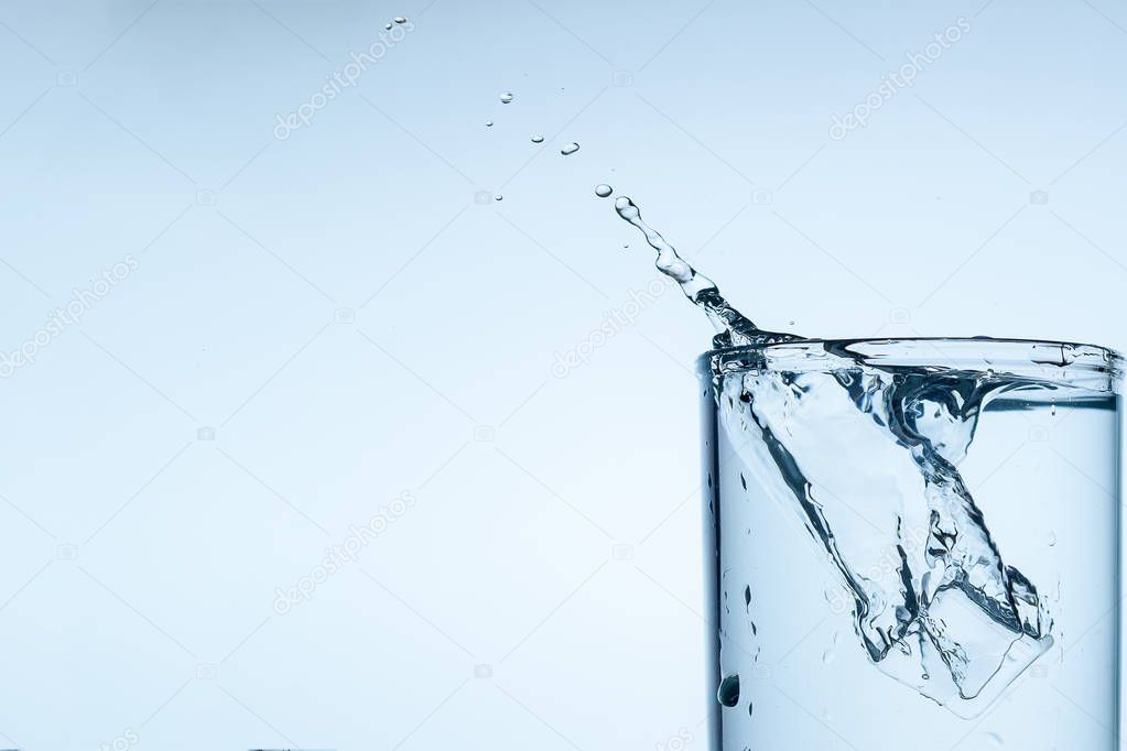 splash of water in glass Cup with ice slice on white background close-up