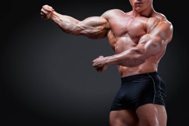 Vücut geliştirmeci kasları gösterir. Hedef ve aspirasyon başarı için. Bedeni üzerinde çalışan, başarılı bir şekilde tamamlandı. Uzun ve zor iş için ödül. Gri bir arka plan üzerinde