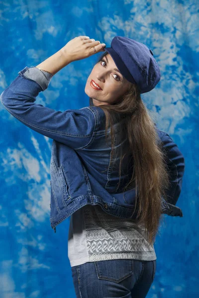girl in denim jacket and cap on blue background