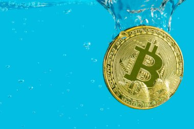 Bitcoin cryptocurrency altın madeni para ile mavi bir arka plan üzerinde boğulma kabarcıklar suya düşüyor