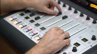 Dengeleyicinin kolçaklarındaki erkek elleri, eşitleyici paneldeki sesi yakın plan, radyo DJ 'i ayarlar.