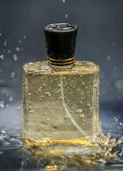a bottle of men\'s perfume with fresh drops of perfume and perfume spray in a transparent bottle