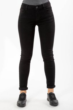 Kotlu kız beyaz arka planda siyah kot pantolon giyiyor.