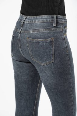 Kot pantolonlu bir kız beyaz arka planda kot pantolon gösteriyor..