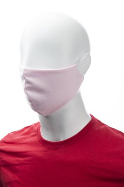 Beyaz arka planda izole edilmiş pembe renkli bir mankenin yüzünde koronavirüse karşı koruyucu yüz maskesi.