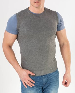 Örgü bir yelek ve beyaz arka planda mavi kot giyen bir adam.