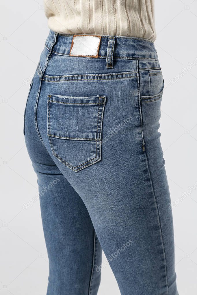 girl in jeans shows off jeans on white background close up, blue jeans