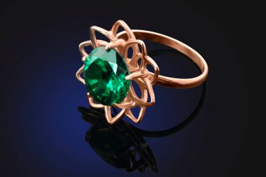 Zümrüt elması olan altın bir yüzük siyah arka planda yansıması olan.