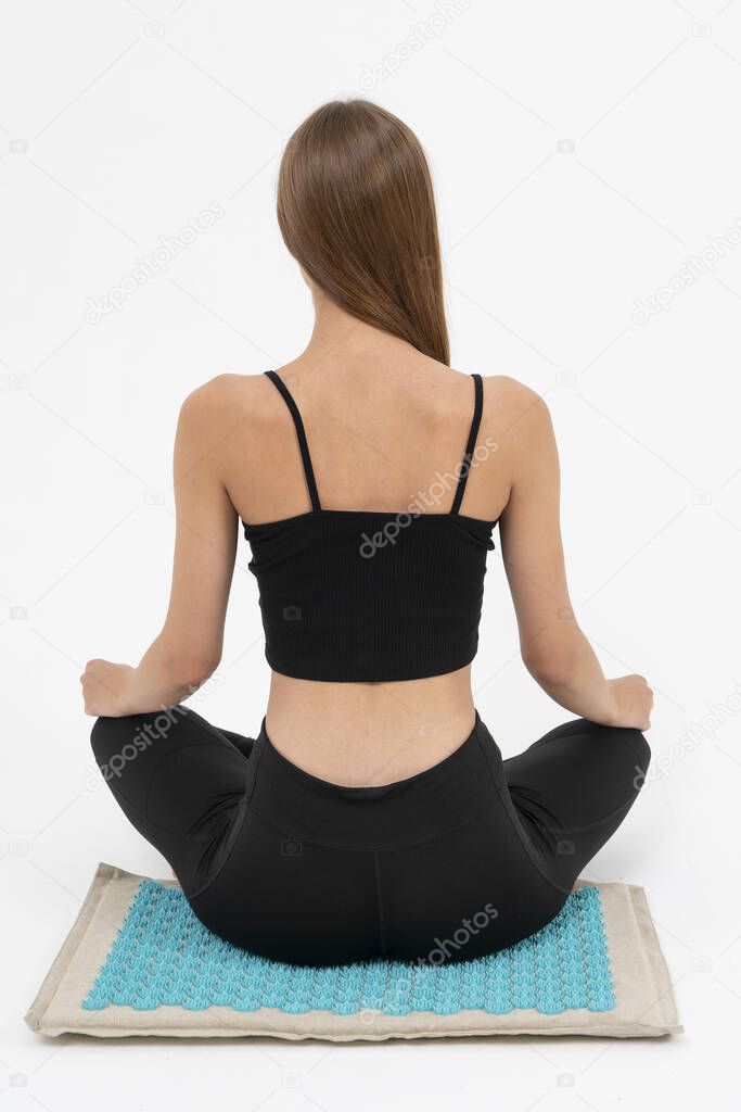 the girl meditates on the massage Mat, she receives acupuncture treatments on a white background