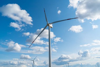 Yeşil alanda güneşli bir günde bir sürü büyük ve yüksek yel değirmeni. Alternatif enerji jeneratörleri. Rüzgar enerjisi. Ekoloji, tasarruf, enerji.