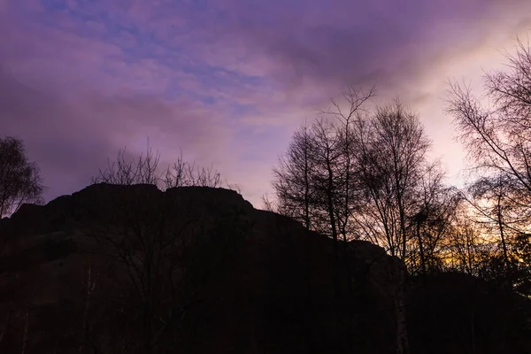 Silhouette of Arthur Seat seen at dawn against purple sky in Edinburgh, Scotland.