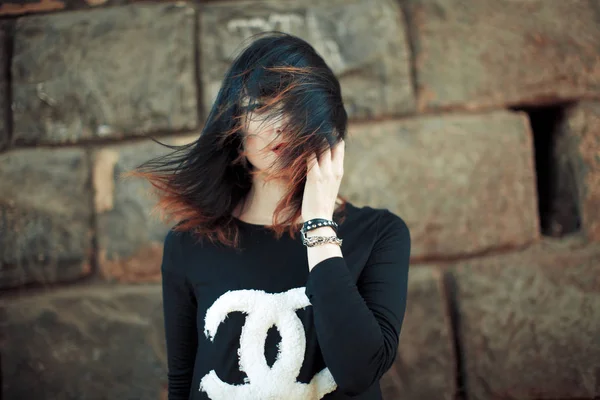 Una chica en un suéter oscuro en un túnel cerca de una pared rocosa . — Foto de Stock