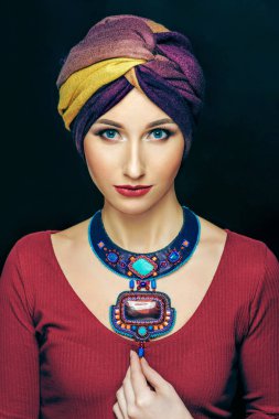 Şapkalı, parlak makyajlı, lüks kolyeli bir kadın.