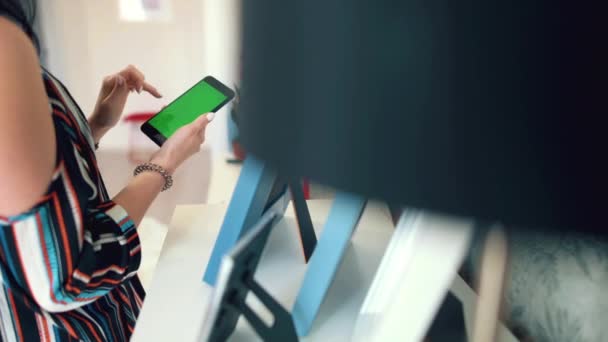 Hermosa chica sosteniendo un teléfono inteligente en las manos con una pantalla verde — Vídeo de stock