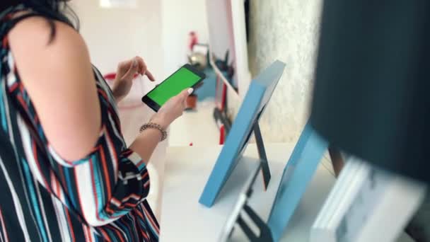 Hermosa chica sosteniendo un teléfono inteligente en las manos con una pantalla verde — Vídeo de stock