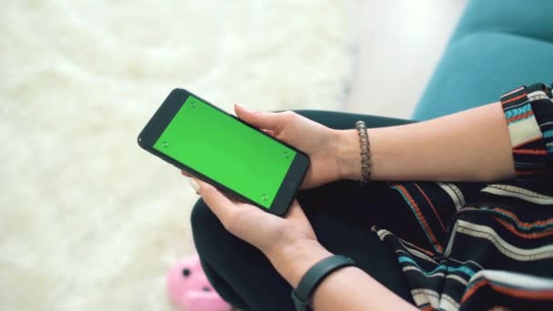 Hermosa chica sosteniendo un teléfono inteligente en las manos con una pantalla verde — Vídeos de Stock