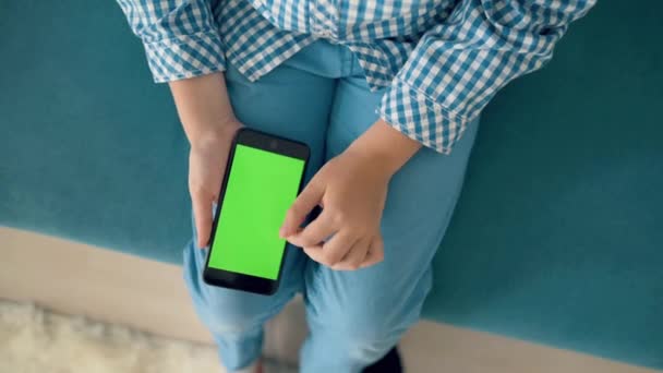 Barnet håller en telefon i handen med en grön skärm — Stockvideo