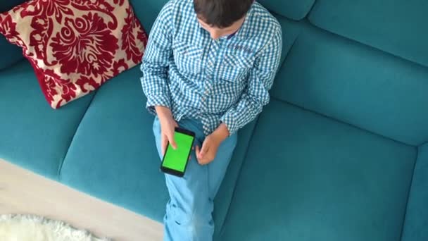 Het kind houdt een telefoon in zijn hand met een groen scherm — Stockvideo