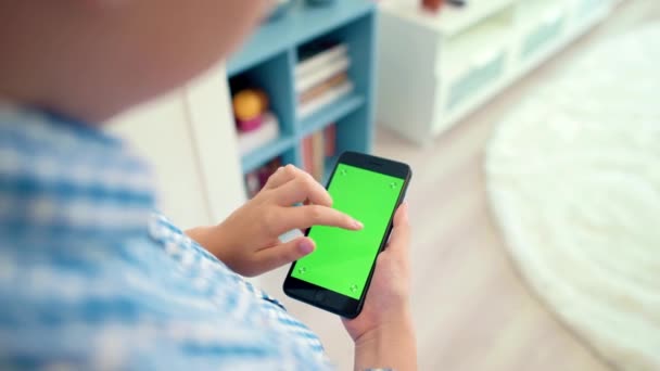 A criança está segurando um telefone na mão com uma tela verde — Vídeo de Stock