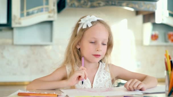 Linda niña se sienta a la mesa y dibuja con lápices . — Vídeos de Stock