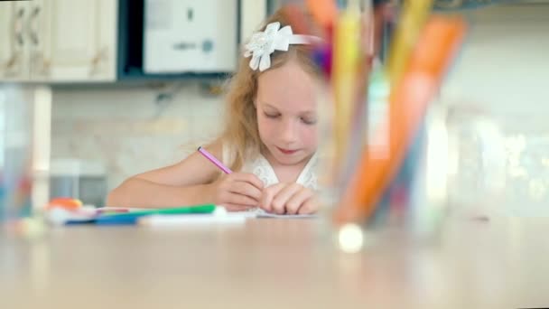 Linda niña se sienta a la mesa y dibuja con lápices . — Vídeos de Stock