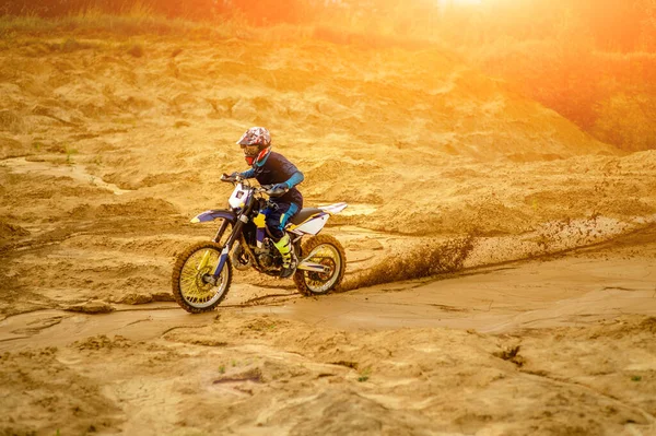 Profesional motociclista Conducir en el desierto y más abajo en la pista Off-Road. Su puesta de sol y pista está cubierta con niebla de humo. Vista lateral . — Foto de Stock