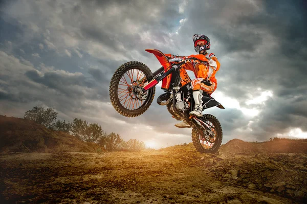 Profesyonel motosiklet sürücüsünün dağlarda ve off-road yolunda ilerleyişinin yan görüntüsü. Gün batımı..
