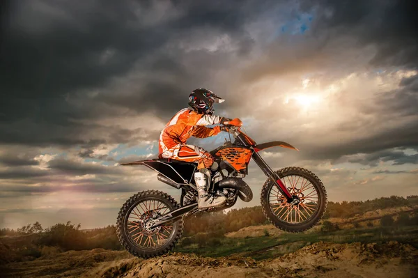 Professionele Motorrijder Rijden op de bergen en verder naar beneden de off-road track. De zonsondergang. — Stockfoto